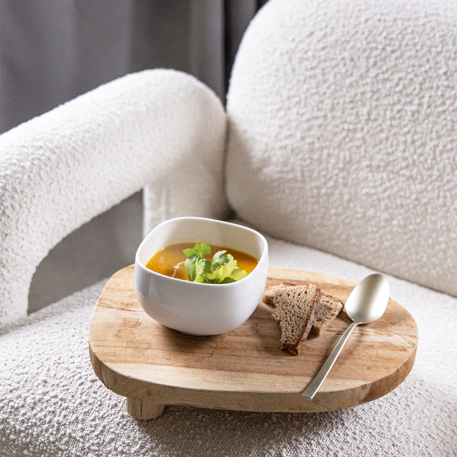 Rosenthal Suomi soup bowl filled with pumpkin soup on a wooden tray placed on a couch